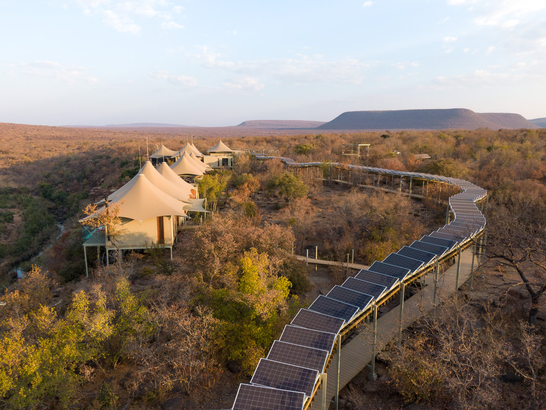 Sustainable eco hotel safari with a pathway shaded by solar panels, low impact tent villas