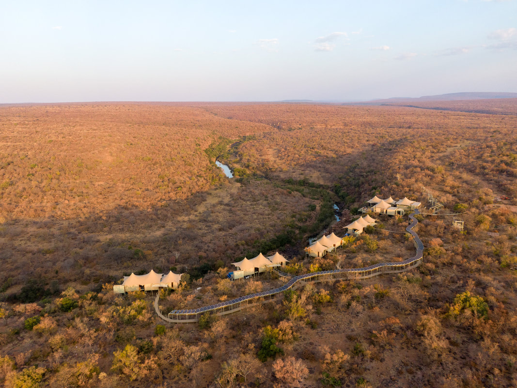 Sustainable eco hotel safari with a pathway shaded by solar panels, low impact tent villas