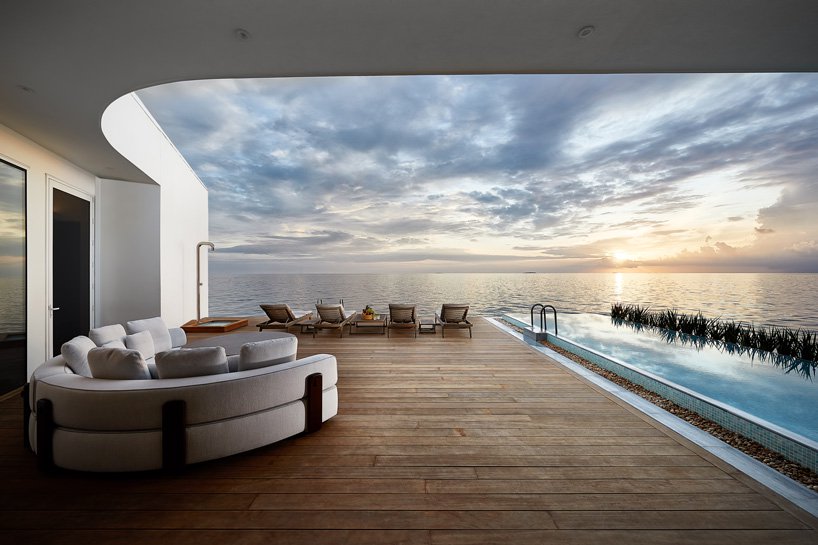 Deck view over looking the infinity pool and out to the Indian ocean horizon at dusk on the over water Maldives villa